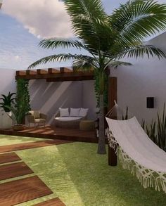 a white hammock sitting on top of a grass covered patio next to a palm tree