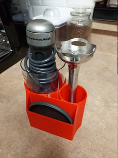 a blender sitting on top of a counter next to an orange cup filled with liquid