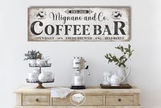 there is a sign that says coffee bar on the wall next to some cups and mugs