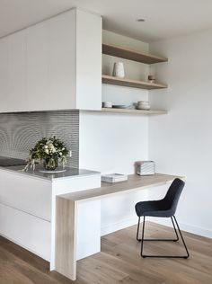 a modern kitchen with white cabinets and wood flooring on the walls, along with a black chair