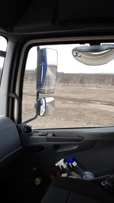 the view from inside a vehicle looking out at an empty field and dirt road in the distance