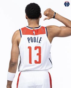 the back of a basketball player's jersey with his hand on his hip and pointing