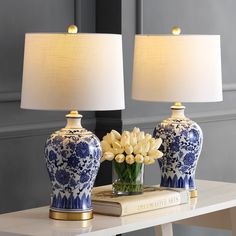 two blue and white vases sitting on top of a table next to a lamp