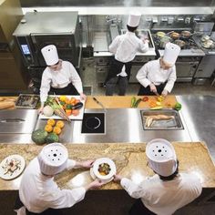 four chefs are preparing food in the kitchen