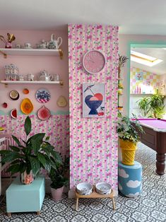 a living room with pink walls and lots of potted plants on the shelves next to it