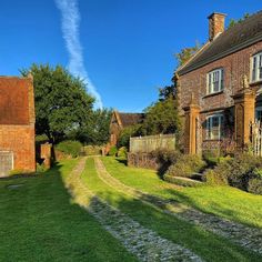 an old brick house with green grass and trees