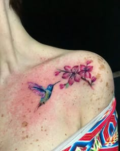 a woman's shoulder with a hummingbird and flower tattoo on it