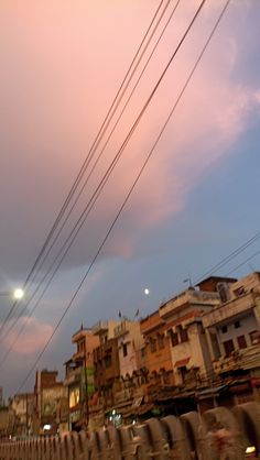 the sky is pink and purple as it passes by some power lines in an urban area