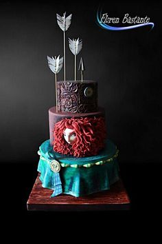 a three tiered cake is decorated with red and blue icing, feathers, and decorations