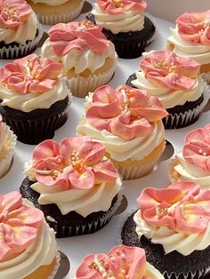 many cupcakes with pink and white frosting on them are arranged in a box