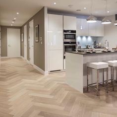 a kitchen with white cabinets and wood flooring next to an island in the middle