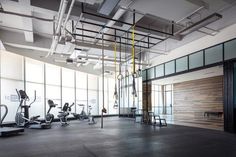 an empty gym with treadmills and exercise machines in the foreground, large windows on both sides