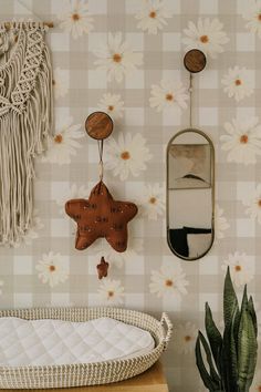 a baby crib next to a potted plant and wall hangings on the wall