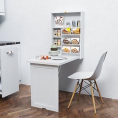 a white kitchen with an open refrigerator and small table next to it on a wooden floor