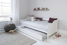 a child's bedroom with a white bed and gray rugs on the floor