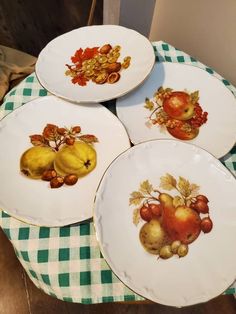 four plates with apples and pears painted on them