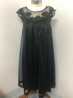 This is a beautiful black nightgown. Label reads Vanity Fair size XS (Extra Small) material is tricot all nylon exclusive of decorations and that the lingerie was made in the USA.  It has tiny flower blossoms along the neckline as decorations.  There is very little wear in the fabric, it's soft and in excellent condition. Black Lace Trim Dress For Night, Sleeveless Party Nightgown With Delicate Lace, Sleeveless Lace Nightgown For Party, Sleeveless Lace Party Nightgown, Black Lace Patchwork Dress For Daywear, Spring Evening Nightgown With Lace Trim, Evening Fitted Nightgown With Delicate Lace, Sleeveless Lace Nightgown For Evening, Evening Lace Nightgown With Lace Trim