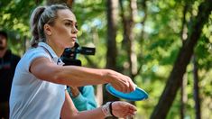 a woman holding a blue frisbee in her right hand