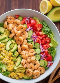 a salad with shrimp, avocado, tomatoes and cucumber in it