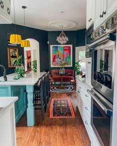 a kitchen with blue walls and white cabinets, an area rug on the floor in front of the stove