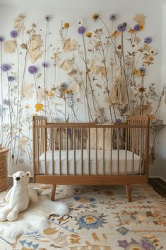 a baby's room with flowers on the wall and a teddy bear sitting in front of it