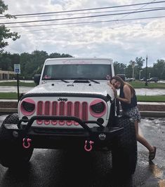 a woman standing next to a white jeep with pink accents on it's hood