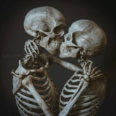 two skeletons hugging each other in front of a black background