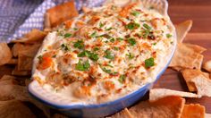 a blue bowl filled with dip surrounded by tortilla chips