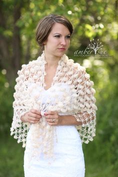 a woman wearing a crochet shawl in the woods with her hands on her chest