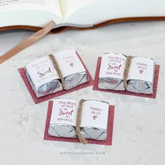 four small candy bars tied with twine on top of a table next to an open book