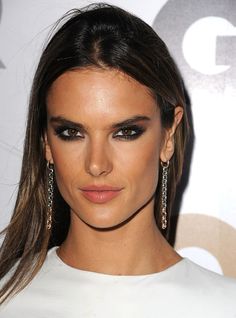 a close up of a person with long hair and smoky eyeshadow wearing earrings