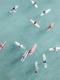 an aerial view of several people on surfboards in the water