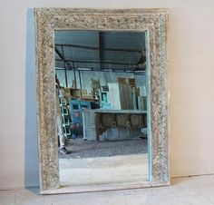 a large mirror sitting on top of a white floor next to a wall with shelves