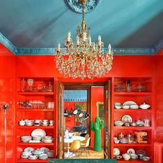 a dining room with red walls and green table cloth on the floor, chandelier hanging from the ceiling