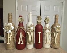 four wine bottles with the word family painted on them, tied to twine and decorated with flowers