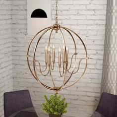 a chandelier hanging over a dining room table with purple chairs and a white brick wall