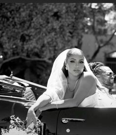 a woman in a wedding dress sitting in the back of a car