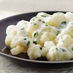 cauliflower covered in white sauce on a black plate