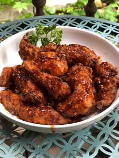 a white bowl filled with chicken wings covered in sauce