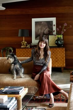 a woman sitting on top of a couch next to a dog