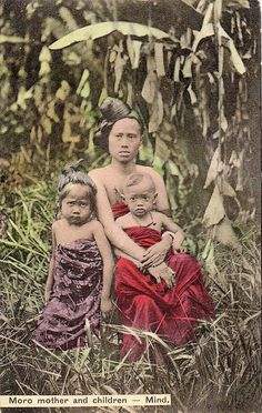 an old photo of two women and a child sitting in the middle of some tall grass