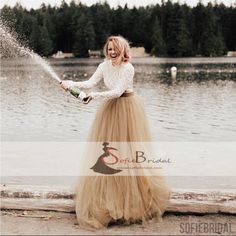 a woman in a long skirt is spraying water on her face and holding a bottle