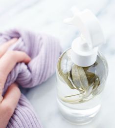 a hand holding a bottle of soap next to a baby's mitt