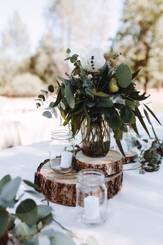 the table is set with mason jars, eucalyptus leaves and candles for an elegant centerpiece