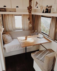 the interior of a small camper with a table and couch in it, next to a window