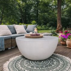 a large white table sitting on top of a wooden floor next to a couch and flowers