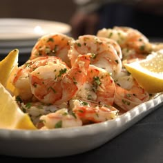 a white plate topped with shrimp and lemon wedges