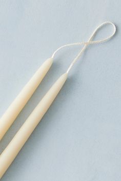 two white candles tied together on a light blue surface