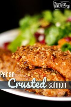 a close up of a plate of food with salad in the background and text overlay that reads, pecan crusted salmon