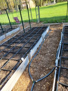 two rows of raised garden beds with hoses attached to them